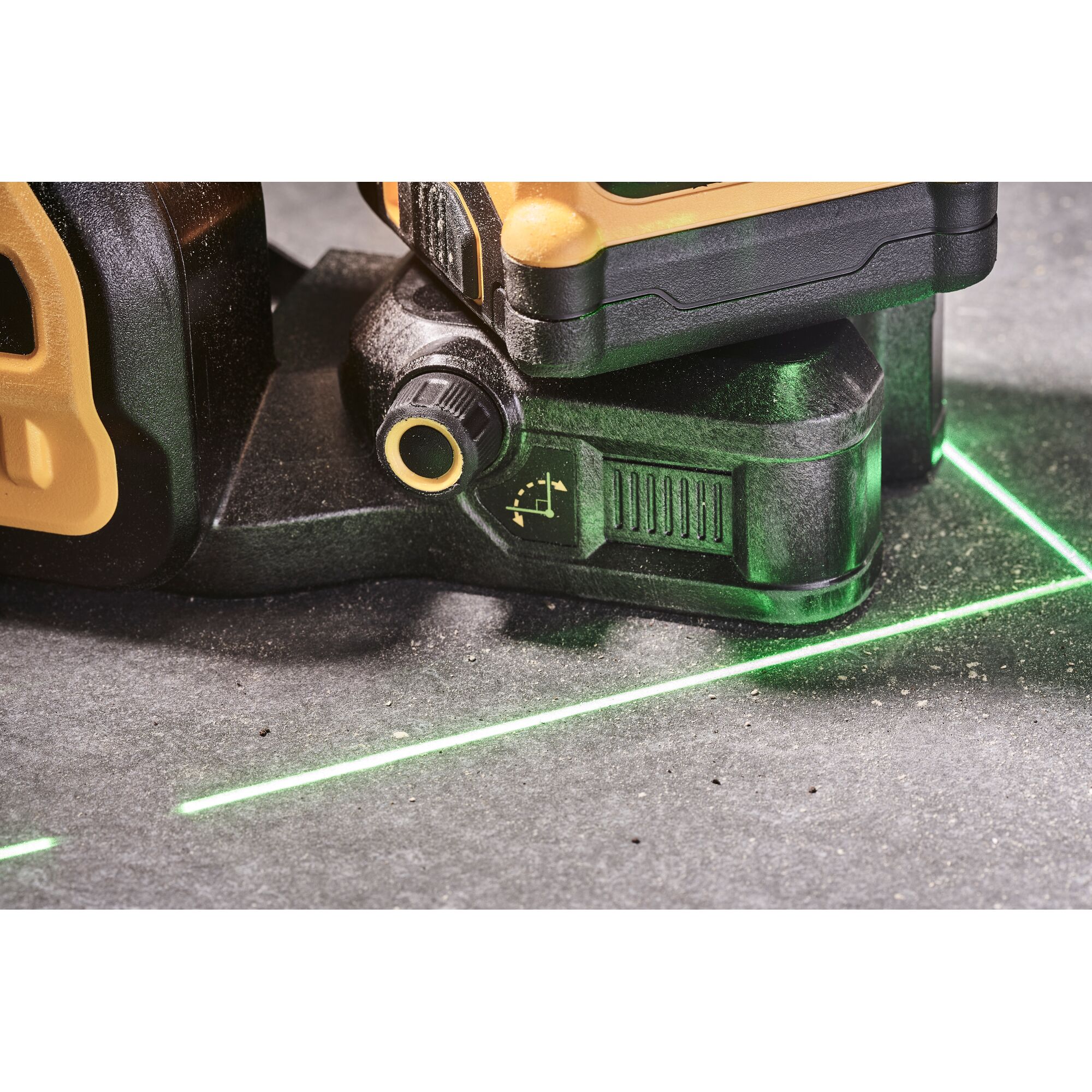 Close-up view of a DEWALT laser level tool projecting green laser lines on a grey surface, used for alignment and leveling tasks.
