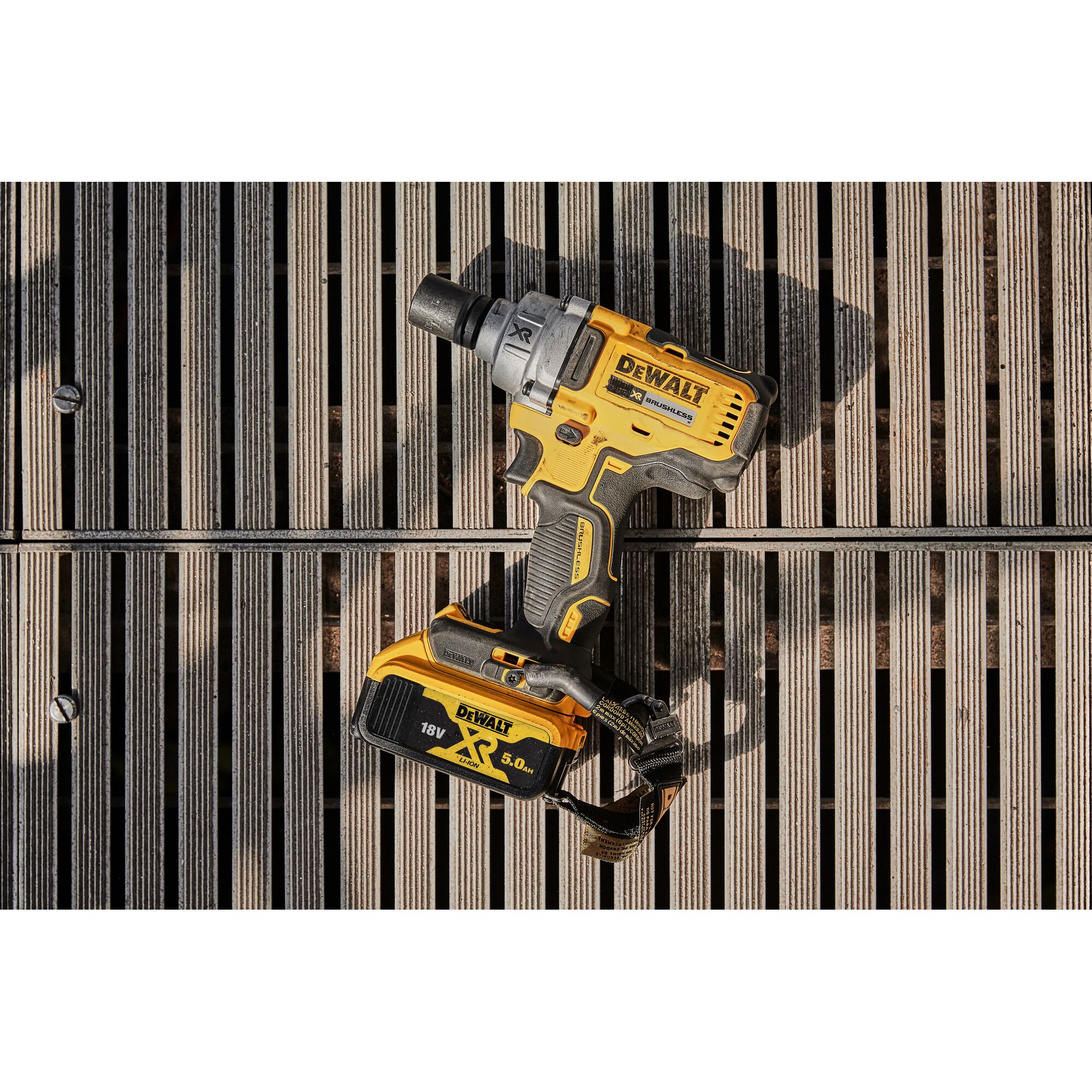 A DEWALT cordless impact wrench, model DCF894P2, with an 18V XR 5.0Ah battery, placed on wooden slats.
