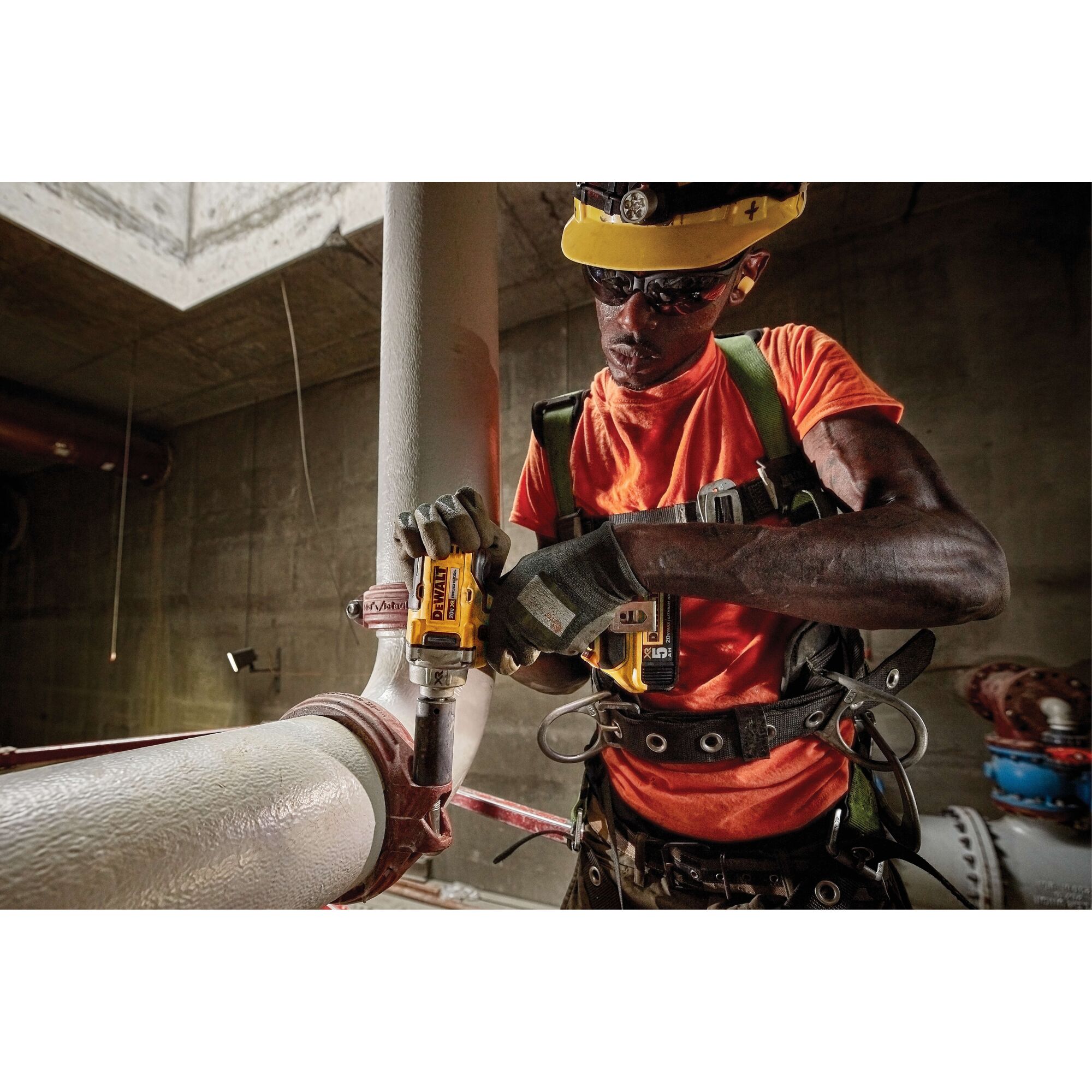 Photo of DEWALT DCF894P2 impact wrench being used on a pipe in industrial setting. Worker wears safety gear.