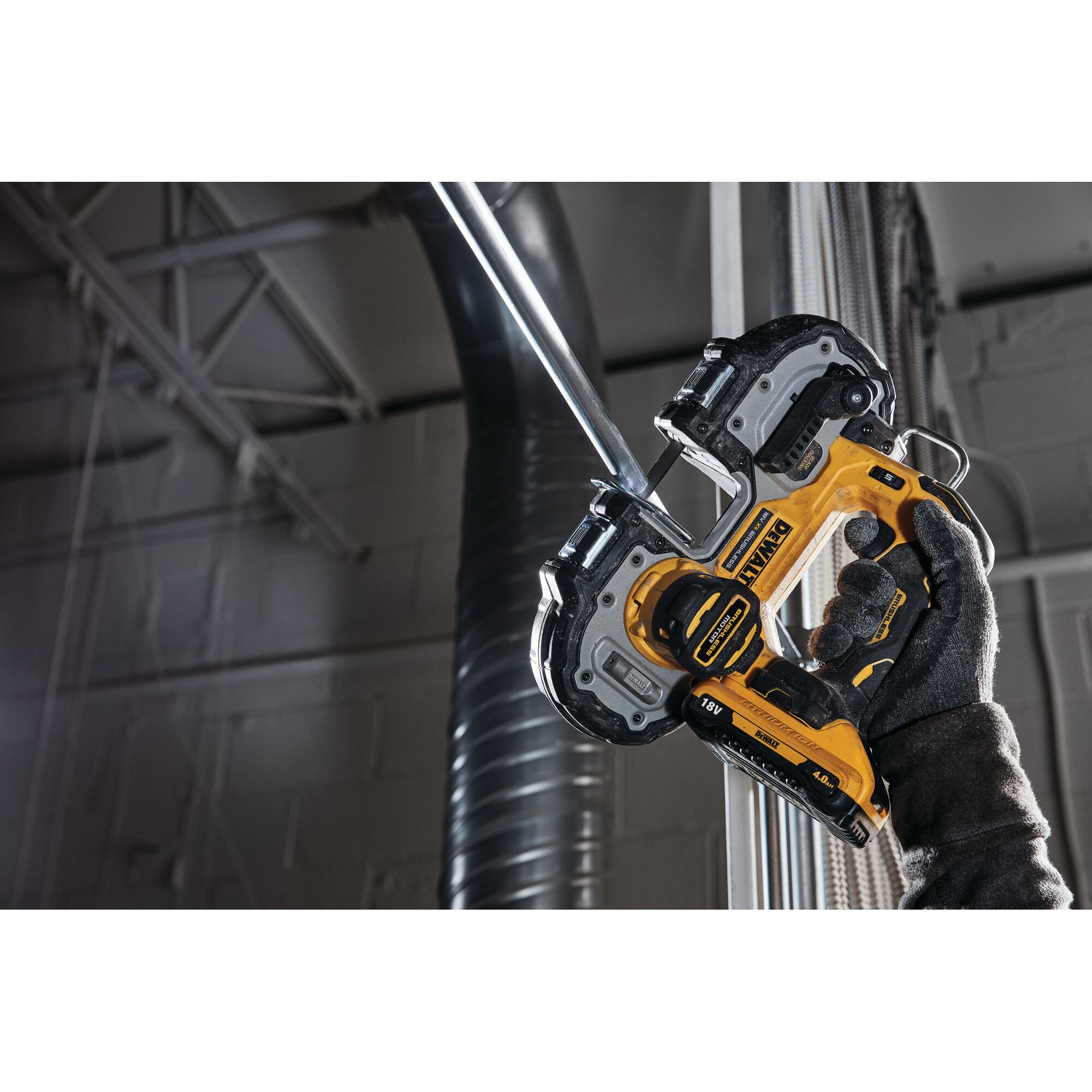 A person wearing a dark work glove is using a DEWALT DCS377NT cordless band saw to cut a metal pipe in an industrial setting.