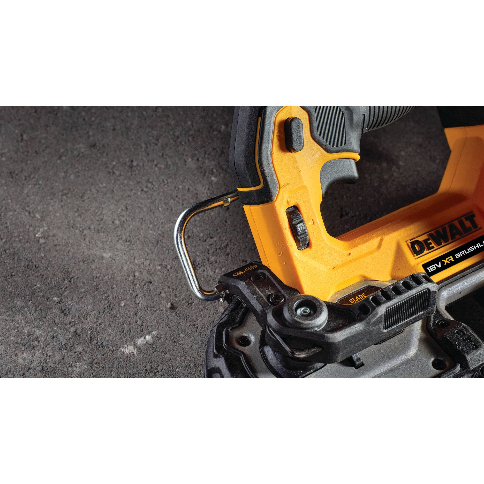 Close-up of a DEWALT 18V XR Brushless power tool, showing the handle, hook, and part of the blade mechanism on a rough, dark surface.