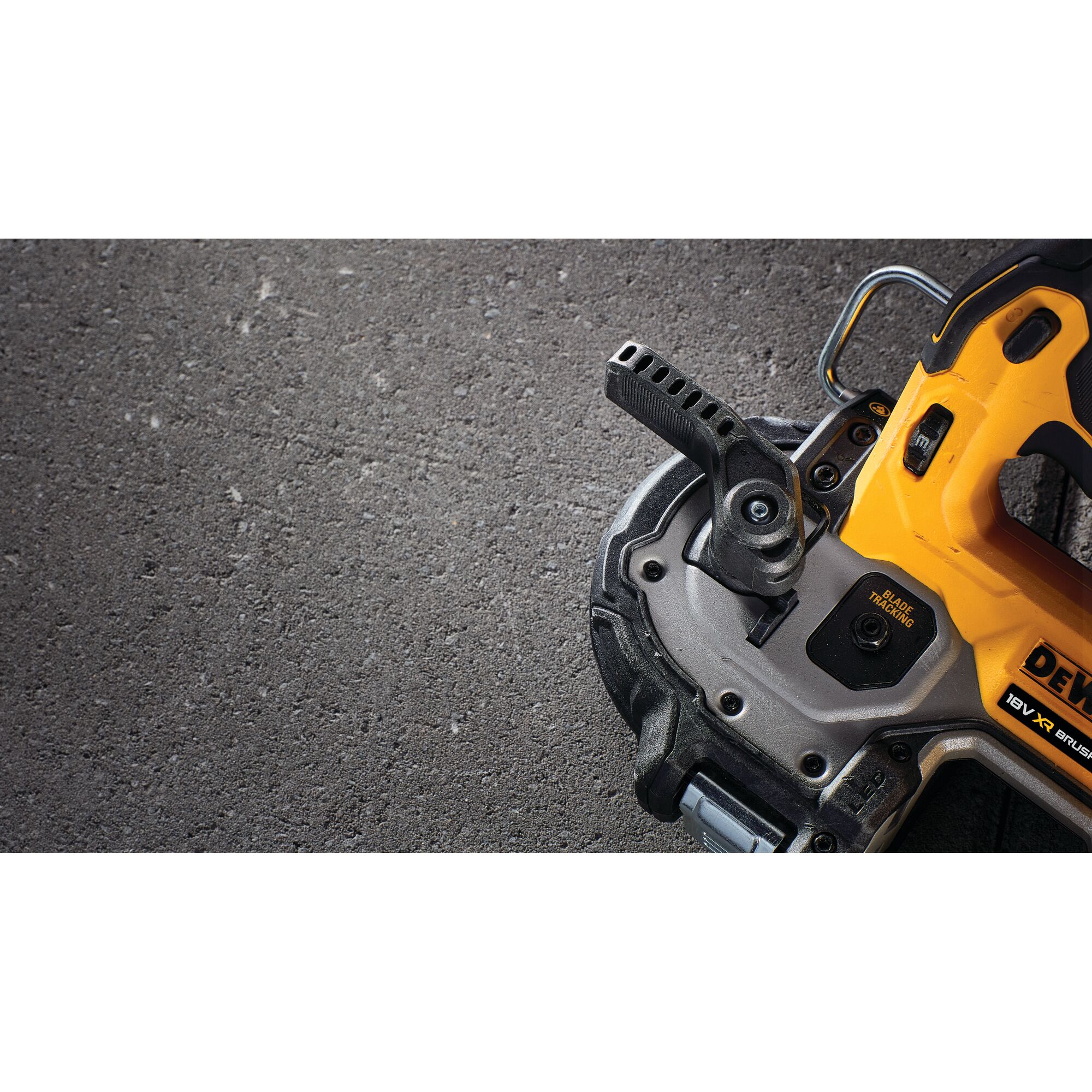 Close-up view of a DEWALT power tool, partially visible, showing its cutting blade and adjustment handle on a rough, gray concrete surface.