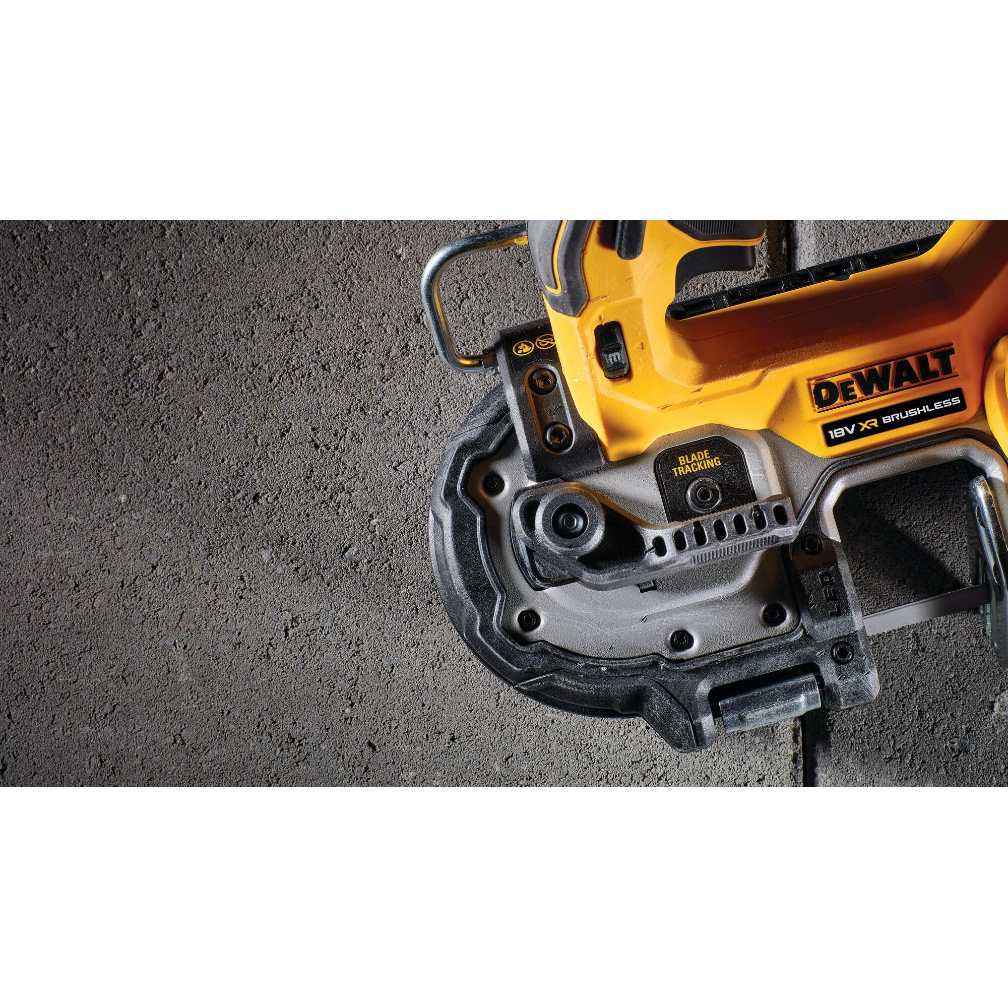 Close-up of a DEWALT 18V XR Brushless power tool, specifically showing the blade tracking feature and part of the handle against a textured concrete surface.