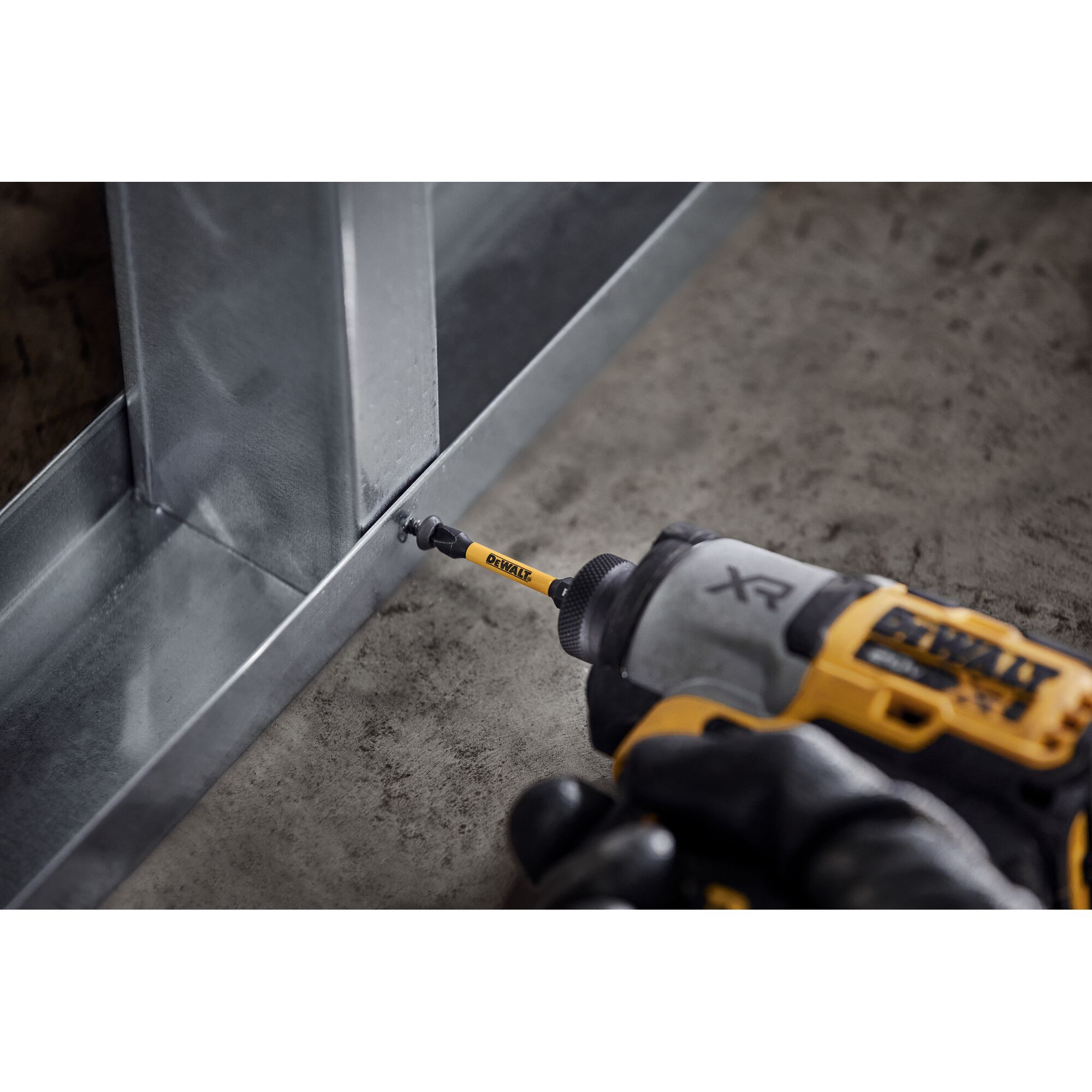 DEWALT drill driving a screw into a metal frame, close-up of tool in use on construction material.