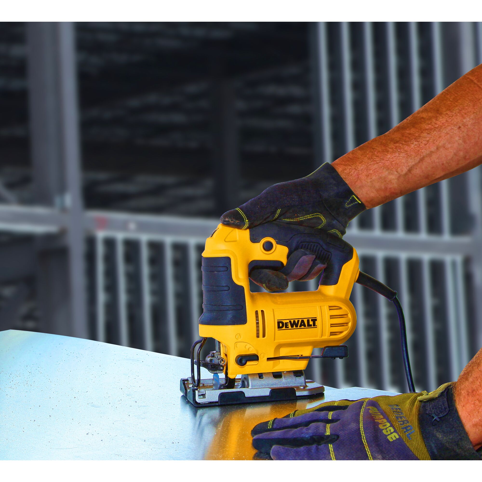 A person wearing work gloves is using a yellow DEWALT jigsaw to cut a piece of metal on a workbench.