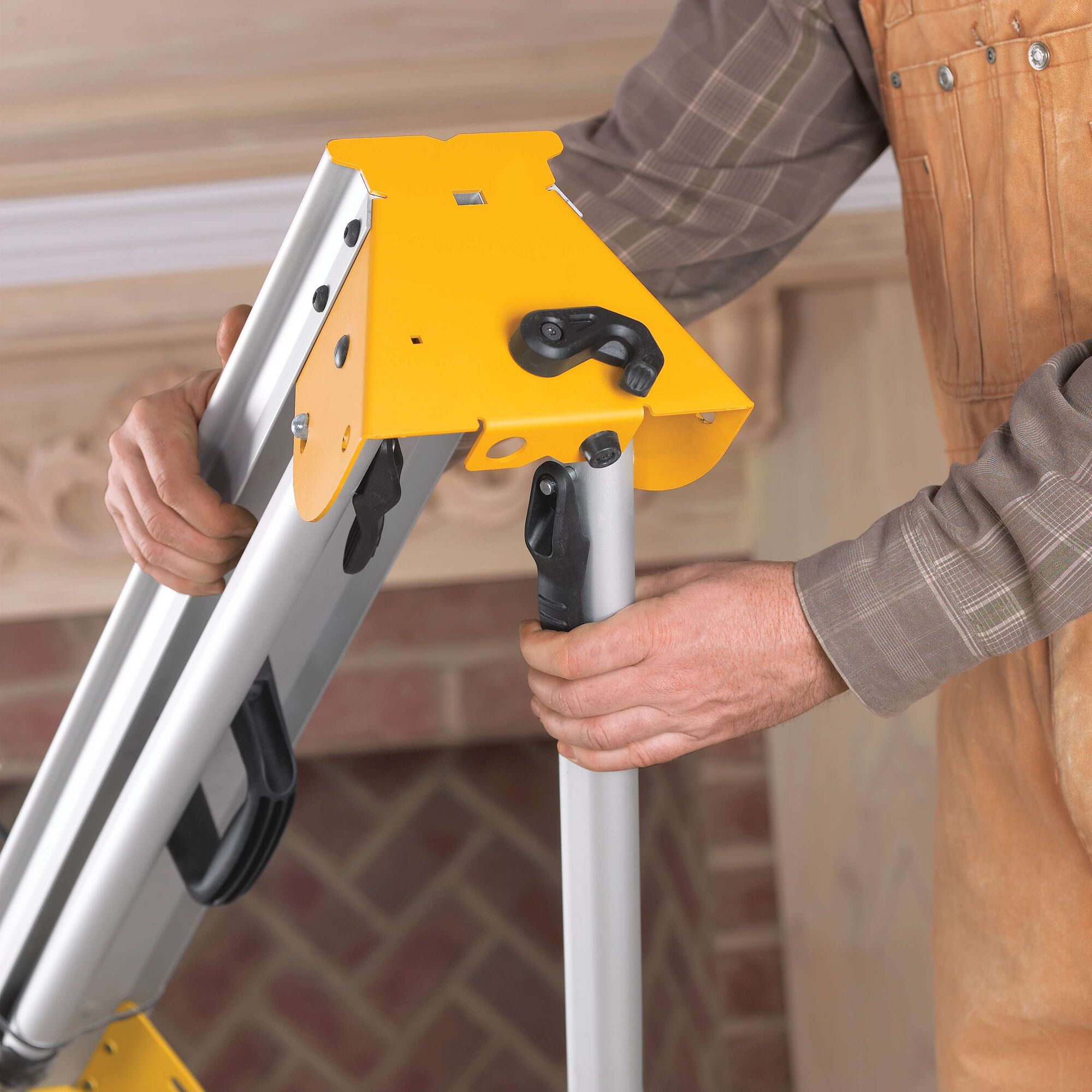A close-up view of a person adjusting the stand of a yellow DEWALT miter saw, focusing on the legs and locking mechanism.