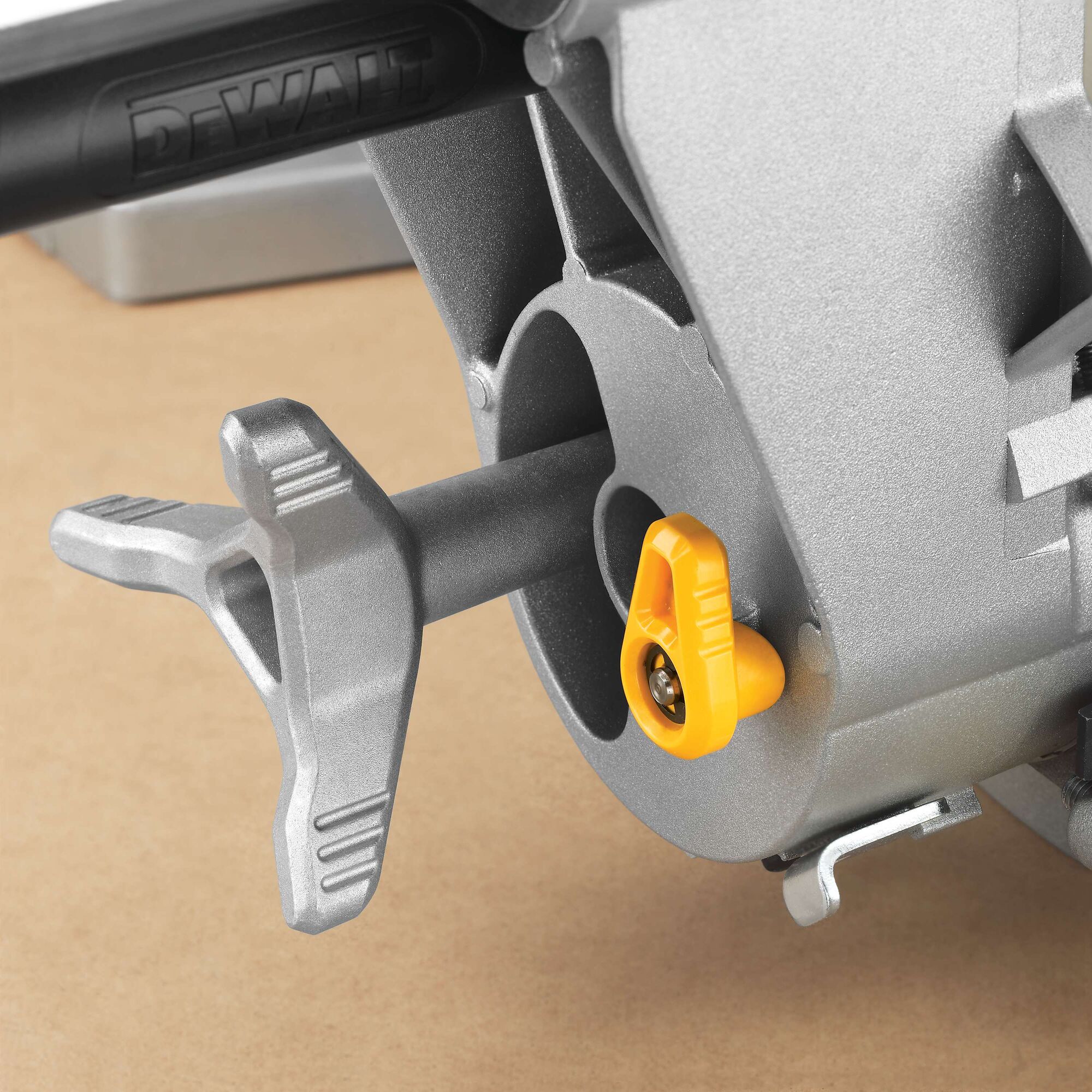 Close-up of a DEWALT DWS780 miter saw component, showing a silver handle and a yellow adjustment knob attached to the metal body.