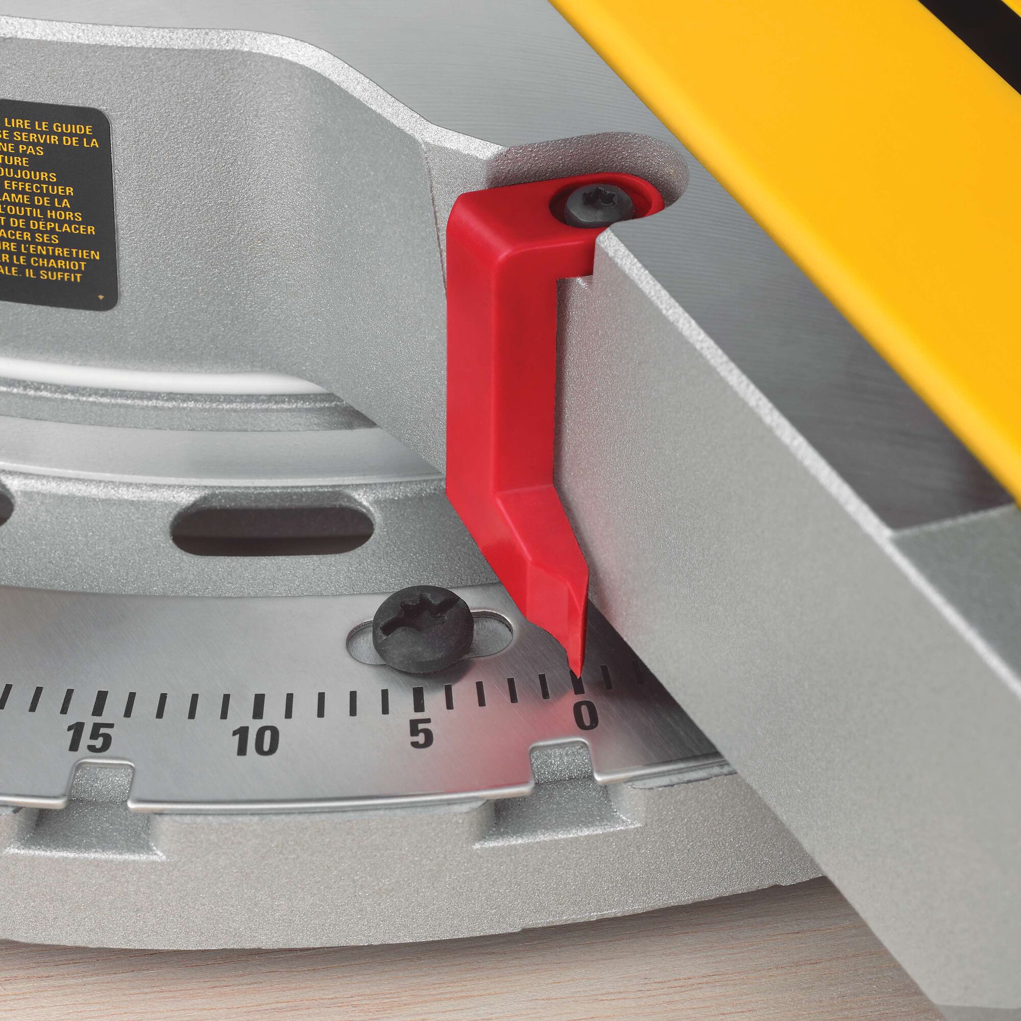 Close-up view of a DEWALT miter saw, focusing on the red indicator pointing to the 0-degree mark on the metal angle gauge.