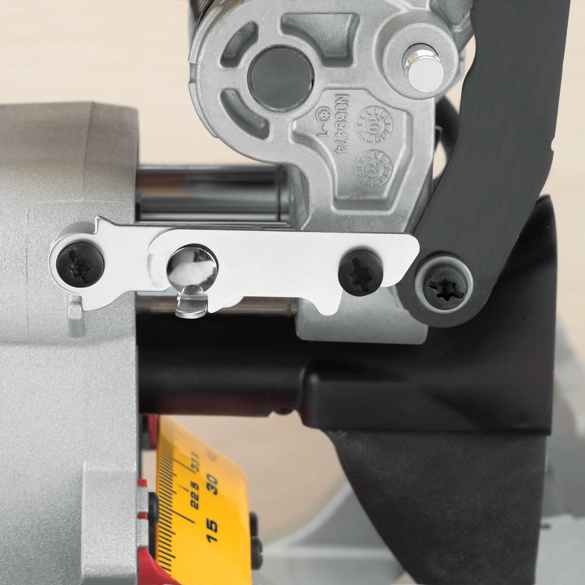 Close-up view of a DEWALT DWS780 miter saw component, showing detailed metal parts and measurement scale.