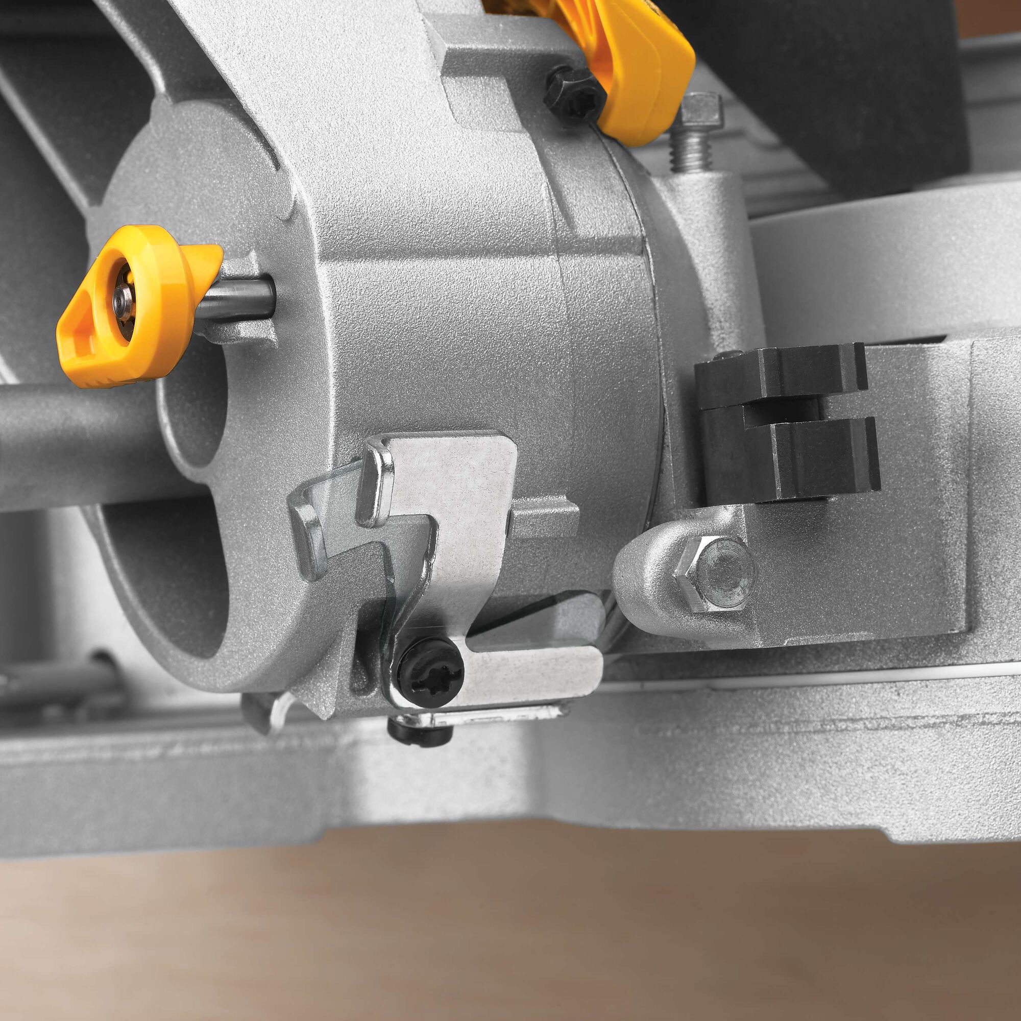 Close-up view of part of a DEWALT DWS780 miter saw, showing the adjustment knobs and metal components in detail.