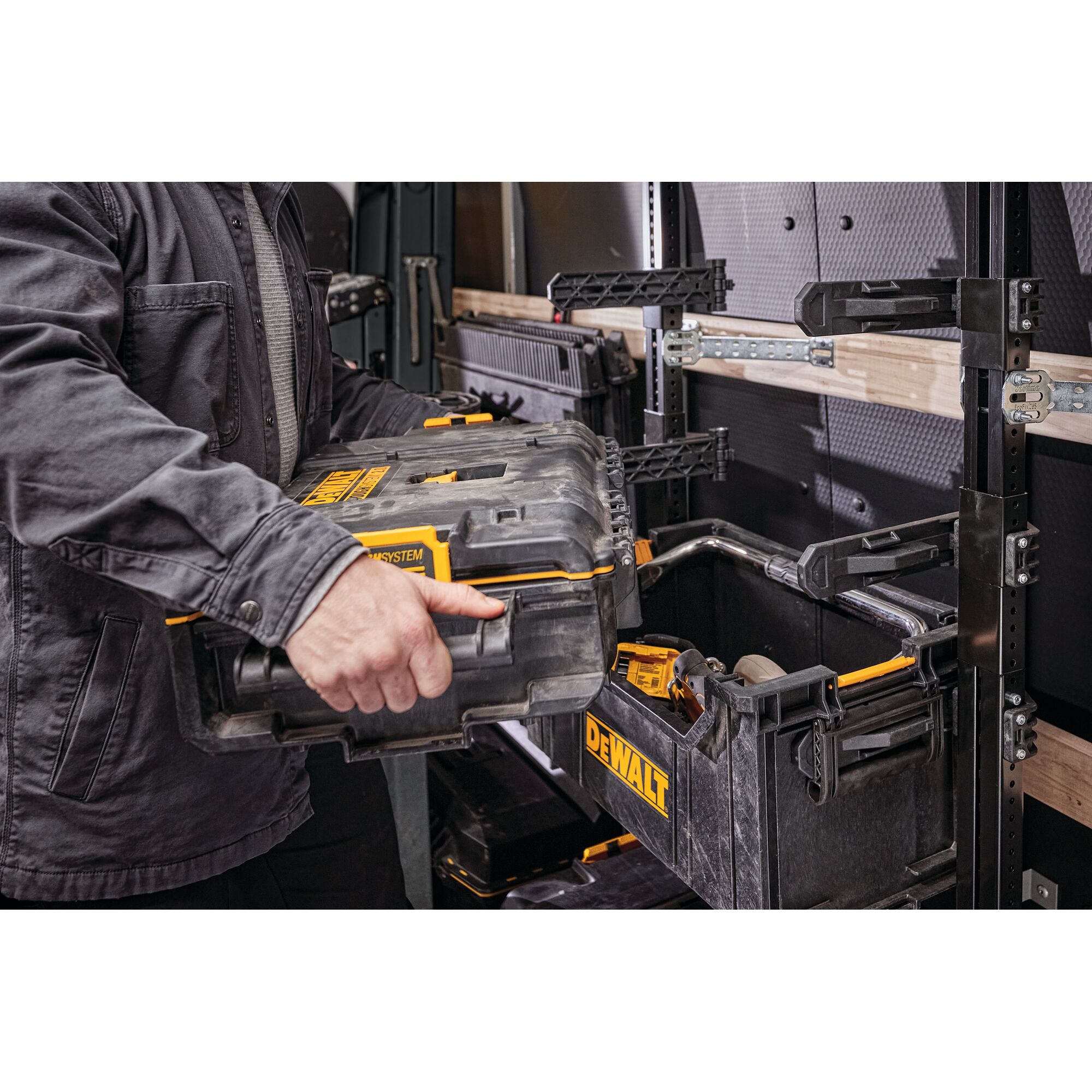 Person places a DEWALT toolbox onto modular rack system inside a workshop or utility vehicle.